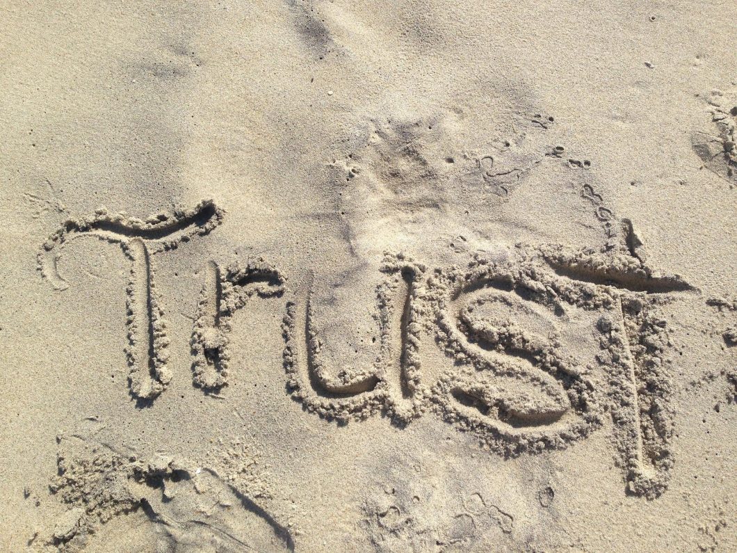 The word trust written in the sand